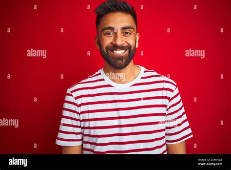 Young Indian Man Wearing Striped T Shirt Standing Over Isolated Red