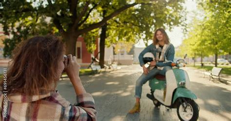 Vidéo Stock Over her shoulder a brunette girl in a checkered shirt uses a camera to photograph