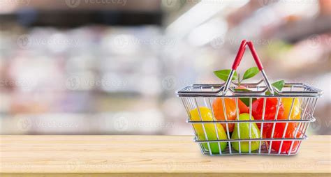 Shopping basket with fruits on wood table over grocery store ...