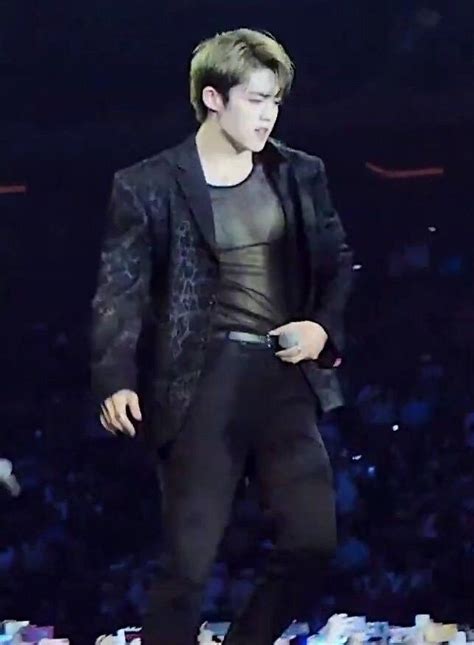 A Male In A Black Suit And White Shoes Is On Stage With His Hands In