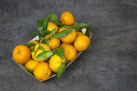 Orange Tangerines With Green Leaves In A Cardboard Tray On A Table