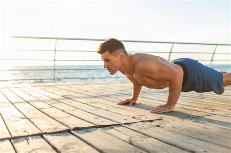 Premium Photo Muscular Handsome Fitness Man With Naked Torso Doing Push Ups On The Beach At