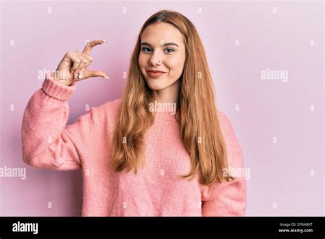 Junge blonde Frau tut Maßnahme Geste mit Fingern lächeln mit einem glücklichen und kühlen