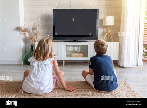 Deux enfants assis au sol du salon et regardant la télévision. Maquette