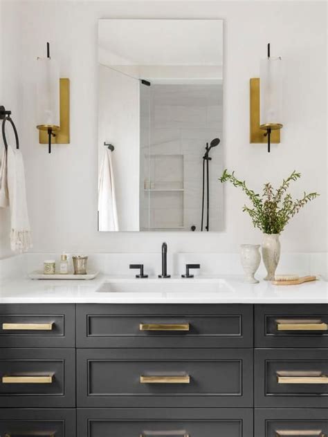 Brass And Glass Sconces Flank A Frameless Vanity Mirror Mounted Above A