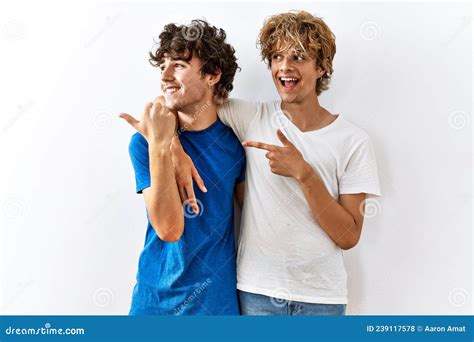 Pareja Joven Gay Parados Juntos En Un Contexto Aislado Sonriendo Con Cara Feliz Y Apuntando