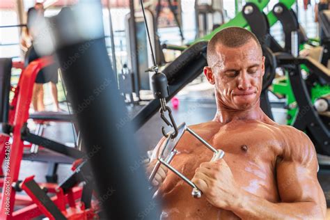 Muscular Male Bodybuilder With Naked Torso Pulling Cable Of Training