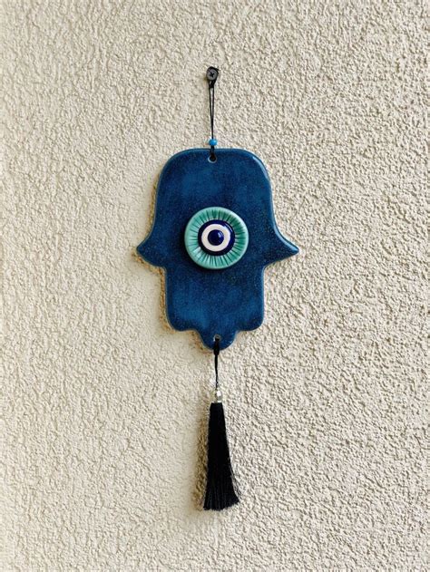 A Blue Hamsa Hanging On The Wall With An Evil Eye