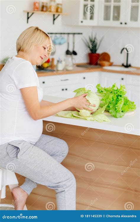 Beautiful Blonde Pregnant Blonde In The Kitchen In Scandinavian Style At The Table Parses Green