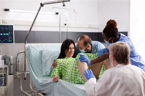 Young Woman Giving Birth To Child In Hospital Ward Maternity With