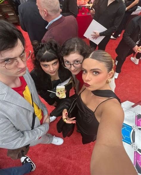 A Group Of People Standing Next To Each Other On A Red Carpet At An Event