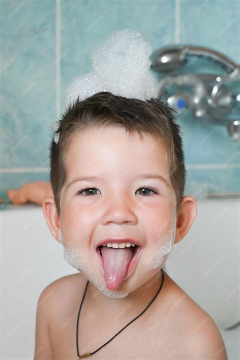 Счастливый забавный маленький мальчик веселится с пеной на голове и ...