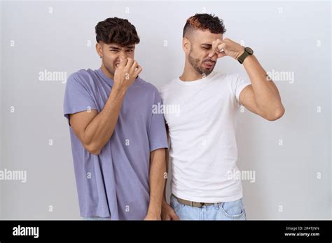Homosexual Gay Couple Standing Over White Background Smelling Something Stinky And Disgusting