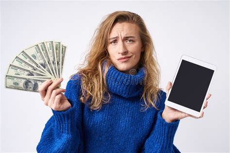Неудовлетворенная курчавая белокурая женщина с планшетом и деньгами в ...