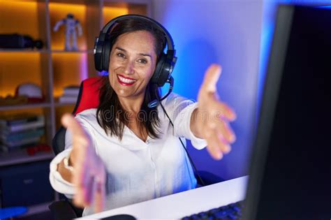 Middle Age Brunette Woman Playing Video Games Looking At The Camera