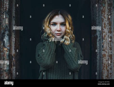 A Beautiful Mysterious Blonde Woman In A Vintage Sweater With A Sad Look Stands In The Doorway