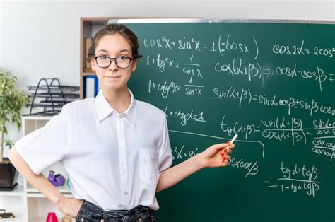 Jeune Femme Blonde Enseignante De Mathématiques Impressionnée Portant Des Lunettes Debout Devant