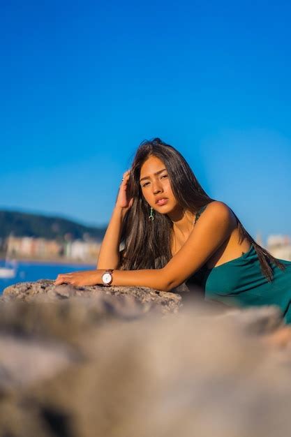 Uma jovem latina desfrutando de um vestido verde nas férias de verão olhando para o mar Foto