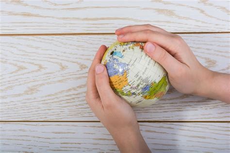 Premium Photo Cropped Hands Holding Globe On Table