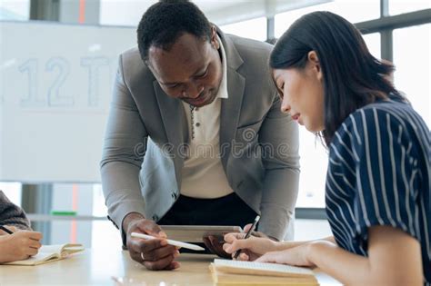 Mature Professor Talking To His Student While Assisting Her On A Class At The University Stock