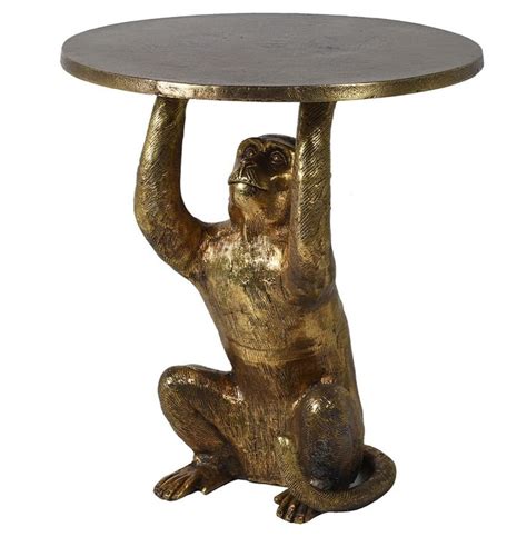 A Gold Monkey Sitting On Its Hind Legs Holding Onto A Round Table