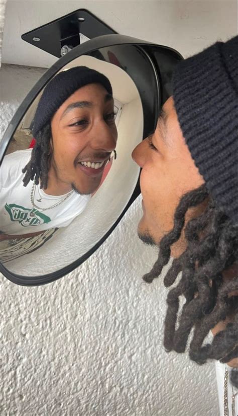 A Man With Dreadlocks Is Looking At His Reflection In The Mirror And