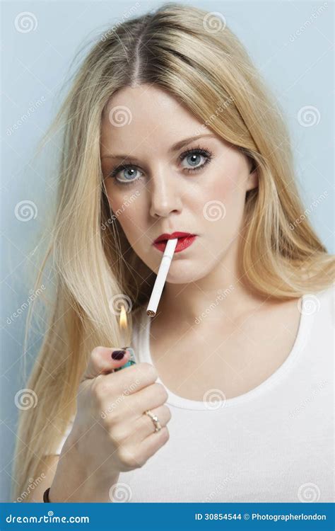Portrait De La Jeune Femme Blonde Mettant à Feu La Cigarette Sur Le Fond Bleu clair Images stock