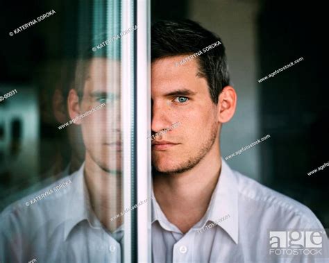 Portrait Of Man Looking Around Glass Door Stock Photo Picture And