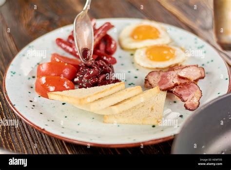 Full English Breakfast On Plate Chef Putting Beans On Plate With