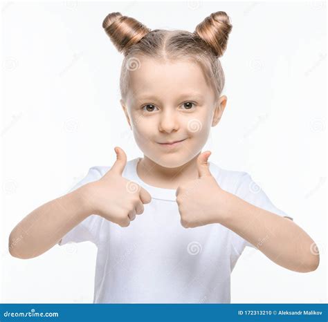 A Small Blonde Girl In A White T Shirt Shows A Like With Two Hands On A White Background Stock