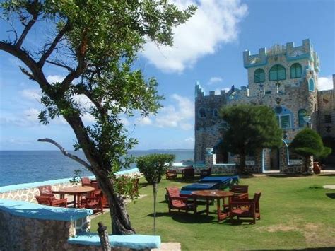 An Outdoor Dining Area With Tables And Chairs Next To The Ocean In