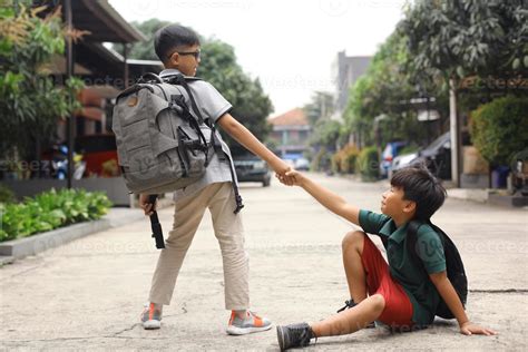 Un Estudiante Ayuda A Levantar A Su Amigo Caído 6757077 Foto De Stock