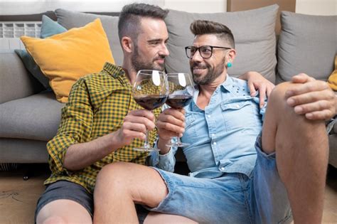 Una pareja gay romántica sonriendo y bebiendo vino en casa Foto Premium