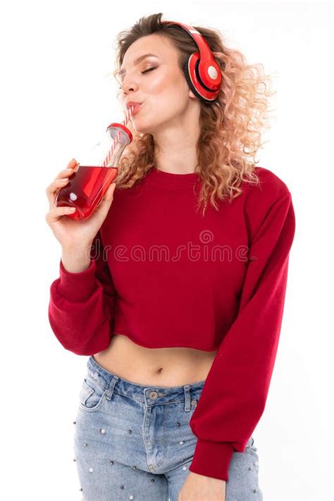 Une Jeune Fille Blonde Aux Casques Boit Du Jus D Un Verre Transparent