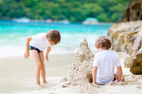 Dos Muchachos Del Niño Que Construyen La Arena Se Escudan En La Playa