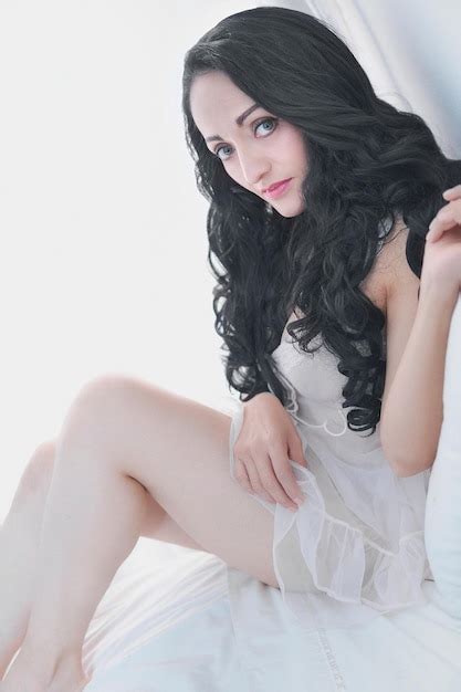 Linda mulher latina em seu quarto confortável em lingerie branca pronta para descansar Foto