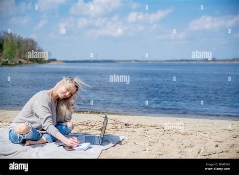Happy Blonde Woman Works Remotely In Beautiful Sunny Weather By The Lake Stock Photo Alamy