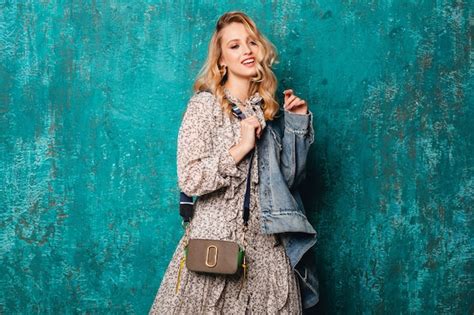 Sexy attraktive stilvolle blonde Frau in Jeans und übergroße Jacke gegen Vintage grüne Wand
