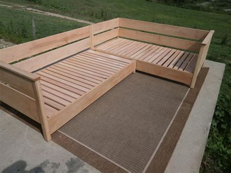 A Wooden Bed Frame Sitting On Top Of A Cement Floor Next To A Green Field