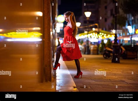 Une belle femme mature dans une robe rouge contrôle de la devanture de nuit avec les lumières de