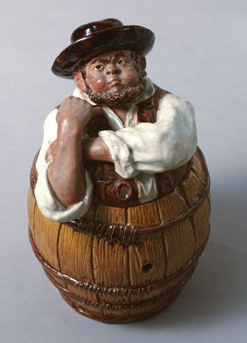 A Ceramic Figurine Of A Man Sitting On Top Of A Barrel With His Arms