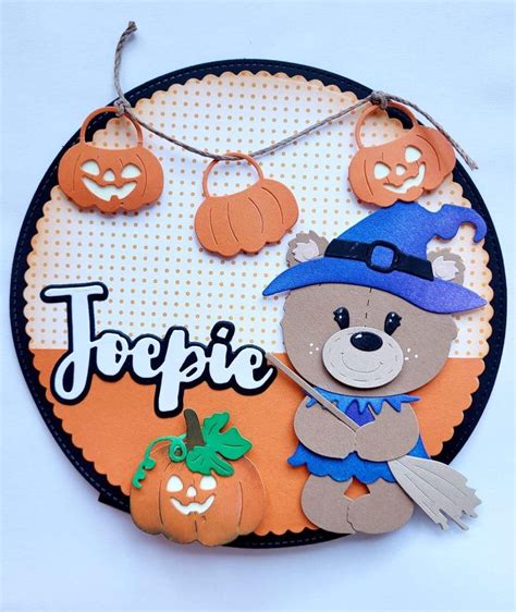 A Teddy Bear Wearing A Witches Hat And Holding A Pumpkin On Top Of A Plaque