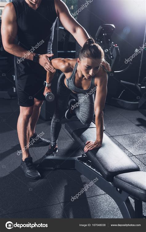 trainer helping woman  exercise  dumbbell stock photo