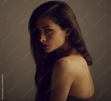 Beautiful Glamour Brunette Woman With Nude Shoulder And Long Curly Hair On Grey Background With