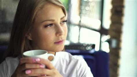Beautiful Blonde Girl With Nude Make Up Wearing White Blouse Sitting In Cafe With Cup Of Coffee