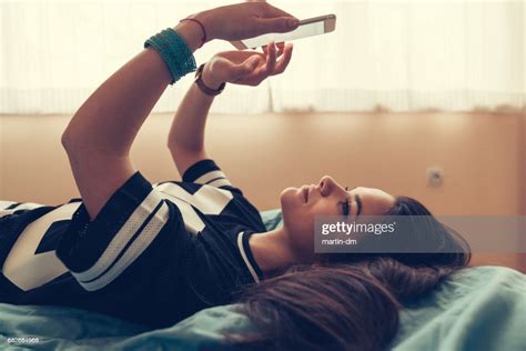 Adolescente Décontractée Dans Son Lit À Laide De Smartphone Photo