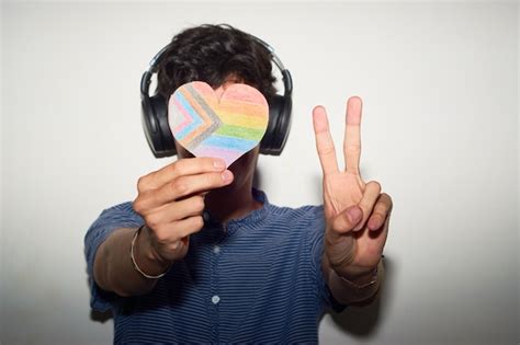 Hombre gay alegre con la bandera del orgullo del arco iris escuchando música Foto Premium