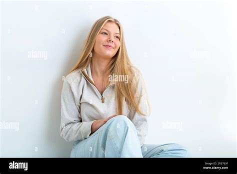 Portrait Of A Year Old Blonde Woman Leaning Against A White Background Looking Away Stock