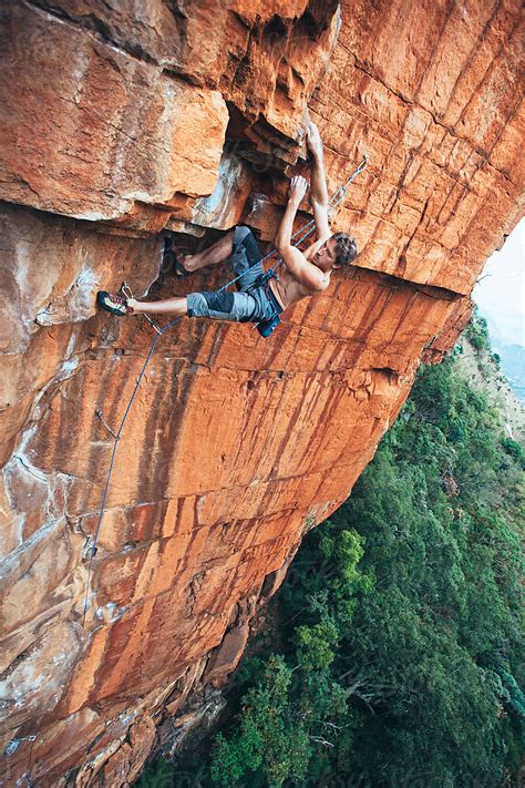 Fit Rock Climber Climbing An Extreme Cliff Face In A Mountain By