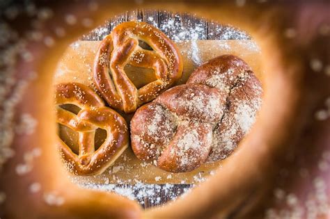 Free Photo Braided Bread And Pretzels On Chopping Board Seen Through Bagels